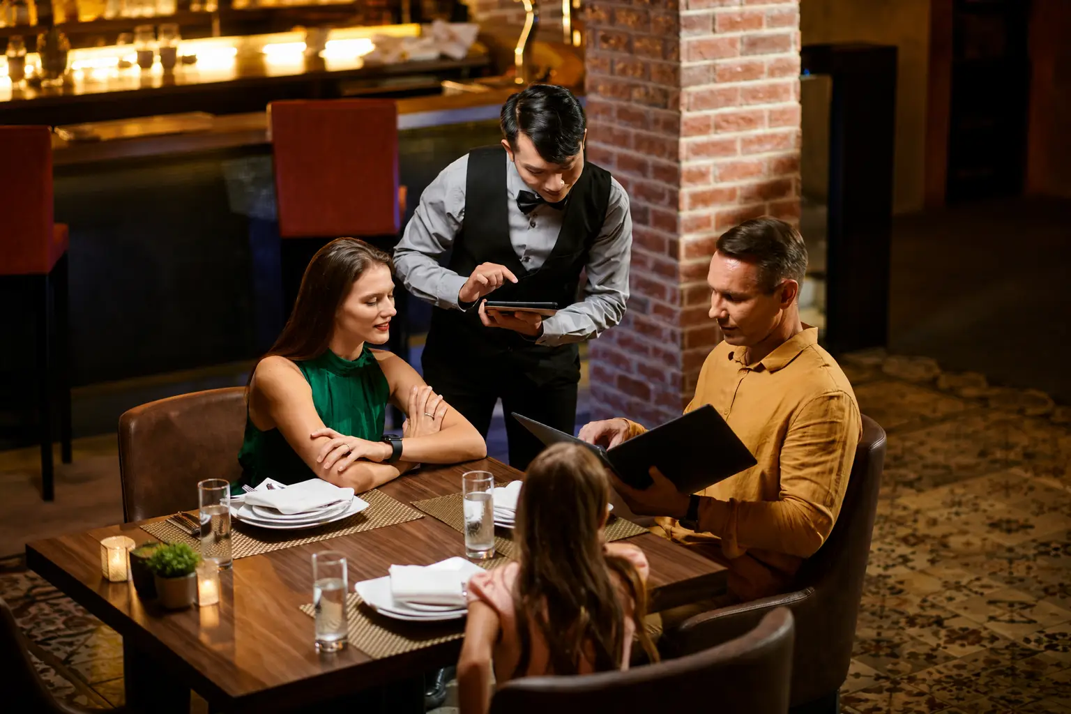 Mesero toma el pedido con una tablet en un restaurante para mejorar la experiencia del cliente mediante marketing automatizado